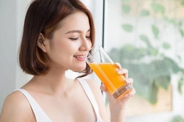 Nên uống nước cam vào lúc nào? Cẩm nang chi tiết cho sức khỏe 2026 Người phụ nữ uống nước cam vào buổi sáng