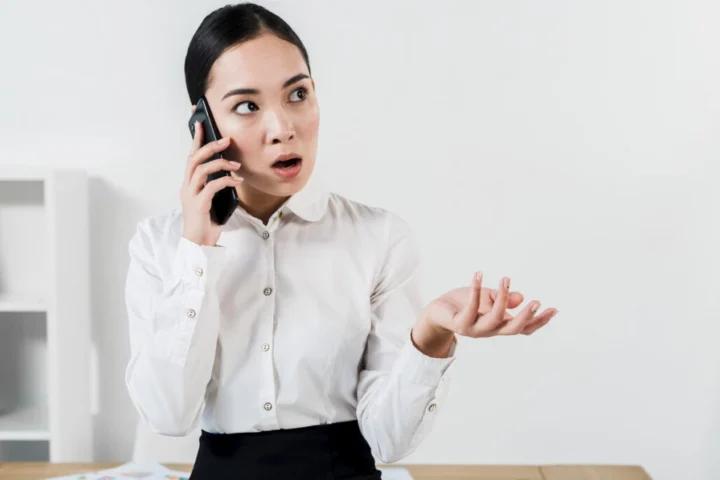 Phụ nữ trẻ đang nói chuyện điện thoại với vẻ mặt cau có